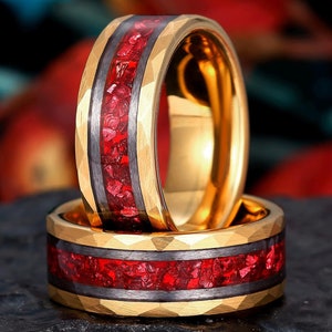 May include: Two gold rings with a black and red inlay. The rings are stacked on top of each other.