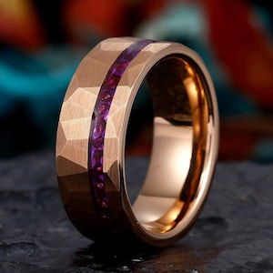 May include: A rose gold tungsten carbide ring with a band of purple gemstones.