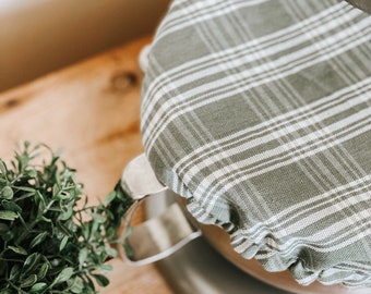 May include: A green and white plaid fabric cover for a kitchen appliance. The cover is made of a soft, cotton fabric and has a simple, elegant design.