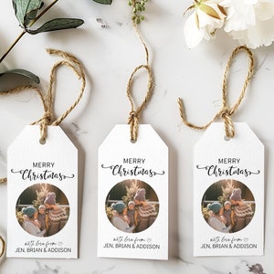 May include: Three white gift tags with a photo of a family in front of a Christmas tree. The tags have the text "Merry Christmas" and "with love from JEN, BRIAN & ADDISON" printed on them.
