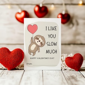 Op de afbeelding: Een Valentijnskaart met een luiaard die een hartvormige ballon vasthoudt. De kaart staat er: "Ik vind je langzaam heel erg leuk" en "Gelukkige Valentijnsdag".