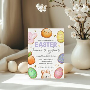 May include: An invitation to an Easter brunch and egg hunt. The invitation features a white background with colorful cartoon cookies, including a bunny, a chick, and an egg. The text reads "Hop on over for an Easter brunch & egg hunt" and includes the date, time, and location of the event.