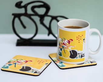 May include: A white ceramic mug with a yellow, red, and blue illustration of cyclists racing. The mug is filled with coffee and has a black handle. The mug is sitting on a coaster with a similar design.