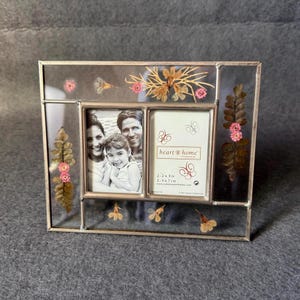 Peut inclure: Cadre photo rectangulaire argenté avec plusieurs ouvertures. Il contient une photo de famille et des fleurs séchées décoratives. Le cadre porte l'inscription "heart home" et les dimensions 2-2x3 in et 2-3x7 cm.