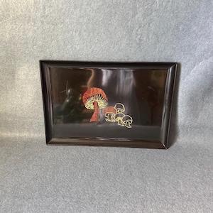 May include: A rectangular dark brown serving tray featuring a central graphic illustration of a large mushroom with a textured reddish-brown cap and several smaller mushrooms outlined in gold, all set against a smooth, glossy surface.