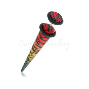 May include: A vibrant, multi-colored ear gauge with a tiger stripe design. The gauge features a gradient of colors, transitioning from red to yellow and green. The gauge has a flared base and a matching top disc, both with black accents.