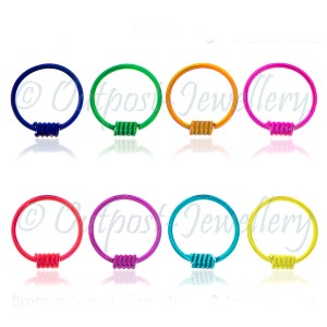 May include: A collection of eight brightly colored nose rings. Each ring has a circular design with a coiled accent. Colors include blue, green, orange, pink, red, purple, teal, and yellow. The external diameter is 8mm.