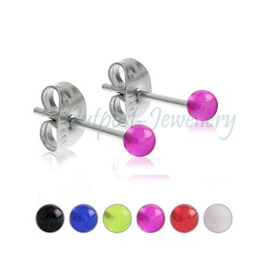 Può includere: Un paio di orecchini a bottone in acciaio inossidabile con perline sferiche rosa acceso. L'immagine mostra anche una selezione di altri orecchini a bottone colorati, tra cui nero, blu, verde, rosso e bianco. Gli orecchini sono esposti su sfondo bianco.