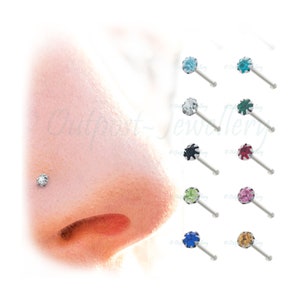 May include: Nose studs featuring a range of coloured gemstones. Each stud has a silver-coloured post and a round, faceted gemstone in shades such as blue, green, and pink. One stud is shown in the nose.