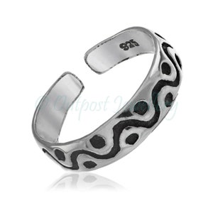 May include: A silver-colored adjustable toe ring with a black, wavy pattern. The ring is open at the top and features the marking "925" on the inside. The design is a series of interconnected, dark-colored shapes.