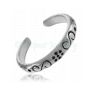 Peut inclure: Une bague d'orteil argent&eacute;e avec un design ouvert. La bague pr&eacute;sente un motif grav&eacute; de volutes et de petits points. Le bijou est con&ccedil;u pour &ecirc;tre r&eacute;glable et est pr&eacute;sent&eacute; sur fond blanc.