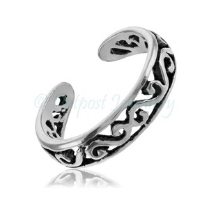 Op de afbeelding: Een zilverkleurige teenring met een open ontwerp. De ring heeft een decoratief, wervelend patroon en is verstelbaar. De ring wordt getoond tegen een witte achtergrond.