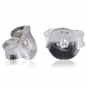 May include: Two silver earring backs, one in profile and one facing forward. The backs are stamped with "925", indicating sterling silver. The design features a post hole and a curved, secure clasp.