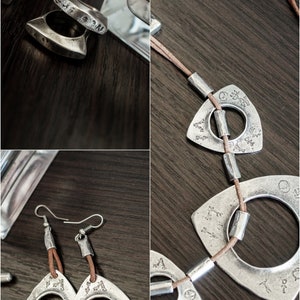 May include: A set of silver jewelry featuring a necklace, earrings, and rings. The necklace has a brown leather cord with silver triangular pendants with circular cutouts. The earrings are similar to the pendants, with a brown leather cord attached to the top. The rings are silver and have a unique, angular design.