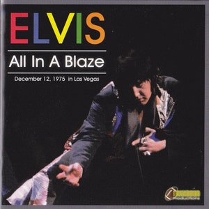 Puede incluir: Una fotografía en blanco y negro de Elvis Presley actuando en el escenario. La foto es de un concierto en Las Vegas el 12 de diciembre de 1975. El texto "Elvis All In A Blaze" está impreso en letras de colores en la parte superior de la foto.