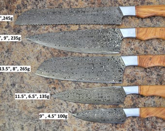 May include: Five Damascus steel kitchen knives with wooden handles are displayed. The knives vary in size, with the largest measuring 15 inches long and the smallest 9 inches. Each blade has a unique pattern, and the handles are a light brown color.