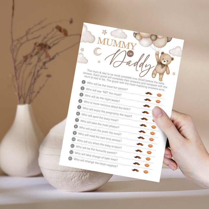 Może przedstawiać: Drukowana karta gry na baby shower z tytułem "Mama czy Tata?" Karta przedstawia brązowego pluszowego misia trzymającego balony i listę 13 pytań dotyczących przyszłych rodzic&oacute;w. Obok każdego pytania znajduje się ikona wąs&oacute;w lub ust, aby goście mogli zaznaczyć swoje odpowiedzi.
