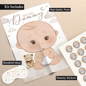 May include: A baby shower game kit featuring a poster with a cartoon baby, a teddy bear, and the words "Pin the Dummy." The kit includes a blindfold mask and dummy stickers. The poster is beige with brown and tan accents.