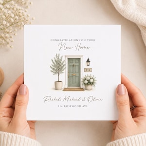 Könnte beinhalten: Eine quadratische Grußkarte mit dem Text CONGRATULATIONS ON YOUR New Home, einer grünen Haustür-Illustration, einem Baum im Topf, einer Pflanze im Topf, einer Wandleuchte, der Nummer 114 sowie den Namen Rachel, Michael & Olivia und 114 ROSEWOOD AVE.