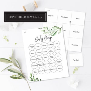 Könnte beinhalten: Eine druckbare Baby-Bingo-Karte mit grünem Blattdesign. Die Karte hat 25 Felder mit babybezogenen Artikeln wie einer Baby-Mütze, einem Babynahrungszubereiter und einem Stofftier. Die Karte ist mit "Baby Bingo" beschriftet und hat ein freies Feld in der Mitte.