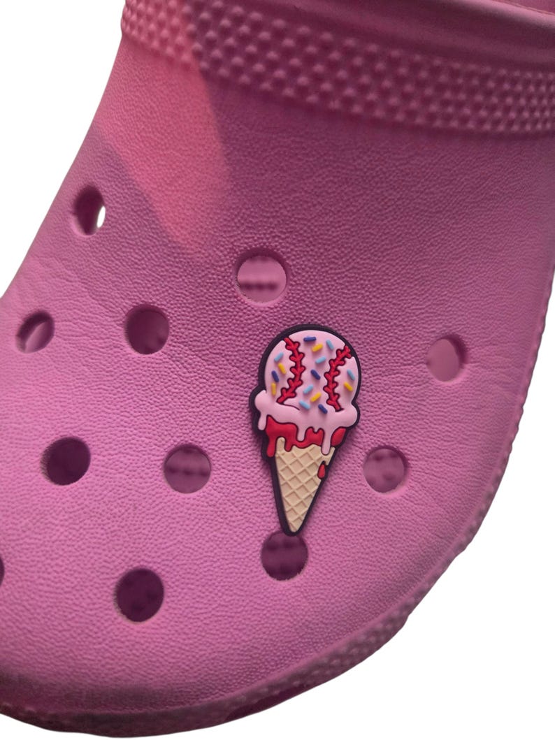 Pode incluir: Um sapato rosa com um adorno de sorvete. O adorno apresenta um cone de waffle com sorvete rosa, gotejamento vermelho e granulado colorido. O sapato tem v&aacute;rios orif&iacute;cios de ventila&ccedil;&atilde;o.