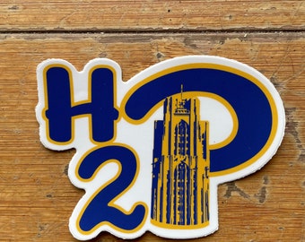 Puede incluir: Una pegatina blanca con un diseño azul y amarillo. La pegatina presenta las letras "H2P" con una imagen estilizada de un edificio en el centro.