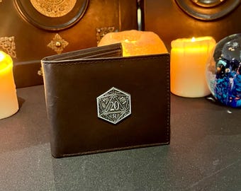 May include: A brown leather wallet with a silver metal D20 die design. The die has the numbers 20, 8, and 14 visible.