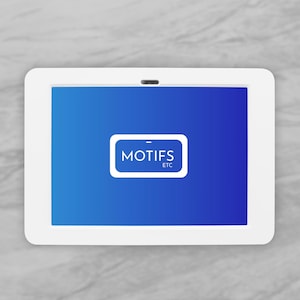 Puede incluir: Una tableta blanca con una pantalla azul que muestra el texto "MOTIFS ETC" en un marco rectangular blanco. La tableta está sobre un fondo de mármol gris.