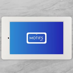 May include: A white tablet with a blue screen displaying the text "MOTIFS ETC" in a white rectangle. The tablet is rectangular with rounded corners and a black dot on the left side. The background is a light gray marble-like surface.