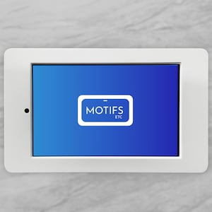May include: A white tablet-like device with a blue screen displaying the text "MOTIFS ETC" inside a white rectangle. The device is set against a light gray, textured background.