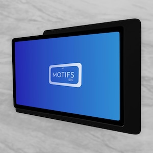 May include: A black rectangular digital display with a blue screen. The screen displays the text "MOTIFS ETC" in a white rectangular box. The display is mounted on a light gray marble-patterned wall.