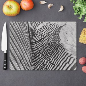 以下が含まれることがあります： 木製のまな板に、線と波の模様が描かれた白黒写真。まな板は木でできており、自然な仕上げになっています。