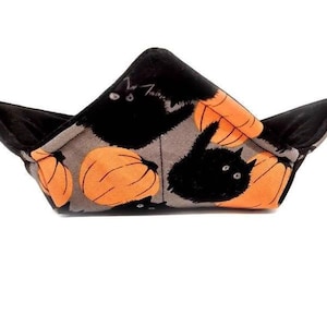 May include: A black fabric bowl with a Halloween theme. The bowl is decorated with black cats and orange pumpkins.