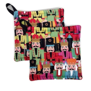 May include: Two red and green pot holders with a pattern of colorful nutcracker figures. The pot holders have black fabric handles.