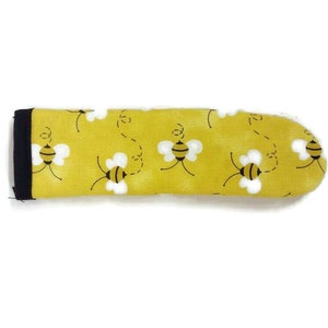 May include: Yellow fabric pot holder with a black trim and a pattern of flying bees.