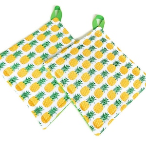 May include: Two green and white pot holders with a pineapple pattern.