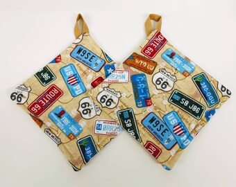 May include: Two square potholders with a tan background are patterned with colorful license plates and Route 66 signs. The potholders have a loop for hanging and are made of fabric. The license plates are from various states.