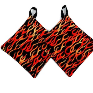 May include: A pair of black pot holders with a flame pattern in shades of orange, yellow, and red.