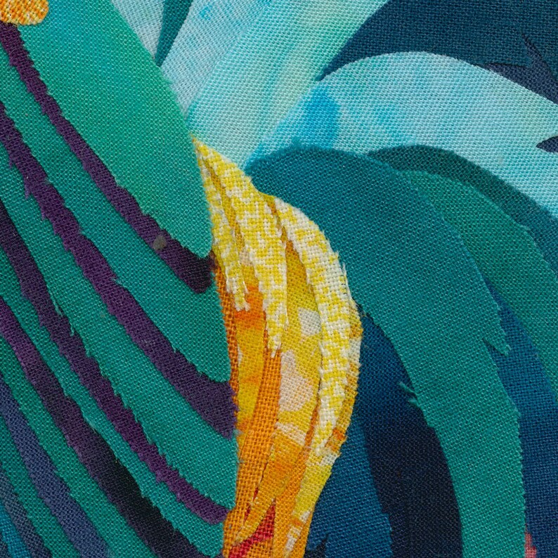 Op de afbeelding: Close-up van een kleurrijk kunstwerk van stof met een mix van turquoise, blauw, geel en oranje stof. De stof is in verschillende vormen geknipt en aan elkaar genaaid om een ​​getextureerd en abstract ontwerp te cre&euml;ren.