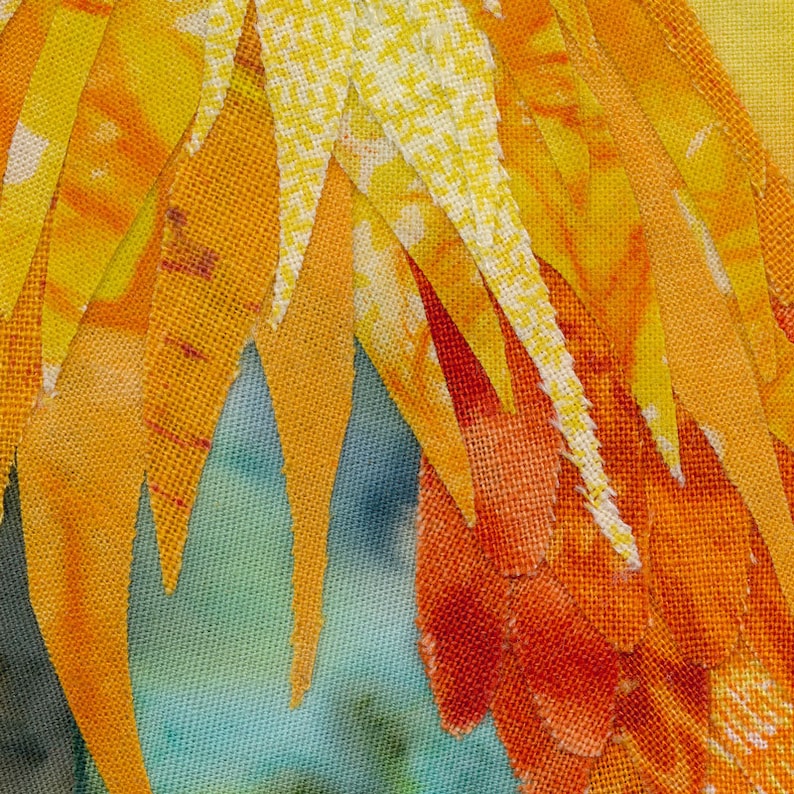Op de afbeelding: Een close-up van een textielweefsel met een patroon van oranje, gele en witte stofstroken. De stofstroken zijn verticaal gerangschikt en overlappen elkaar.