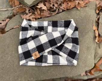 May include: Black and white buffalo check fabric headband with a small brown logo in the centre.