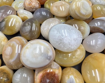 May include: A collection of smooth, polished agate stones in various shades of white, yellow, and brown. The stones have a natural, organic look and are perfect for use in crafts, jewelry making, or as decorative accents.