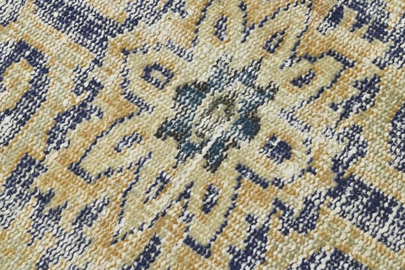 May include: Close-up of a woven rug with a geometric pattern in shades of blue, beige, and white.