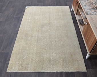 May include: A light beige area rug with a subtle pattern. The rug has a slightly distressed look and is made of a soft, plush material.