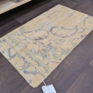 K&ouml;nnte beinhalten: Ein hellbeiger Teppich mit einem blauen und gr&uuml;nen Blumenmuster. Der Teppich liegt auf einem dunklen Holzboden.