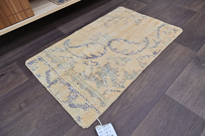 K&ouml;nnte beinhalten: Ein hellbeiger Teppich mit einem blauen und gr&uuml;nen Blumenmuster. Der Teppich liegt auf einem dunklen Holzboden.