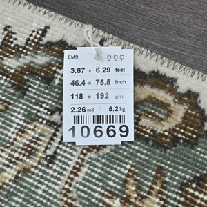 Op de afbeelding: Een wit label met zwarte tekst en een barcode. Het label geeft de afmetingen van een tapijt in voet, inch en centimeter. Het tapijt is 3,87 voet bij 6,29 voet, 46,4 inch bij 75,5 inch en 118 centimeter bij 192 centimeter. Het label geeft ook het gewicht van het tapijt aan, dat 5,2 kilogram is, en de oppervlakte, die 2,26 vierkante meter is. Het barcodenummer is 10669.