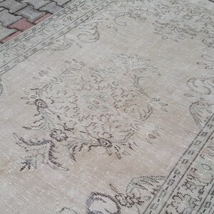 May include: A vintage rug with a faded floral pattern in shades of gray and white. The rug has a distressed look and is made of a soft, natural fiber.