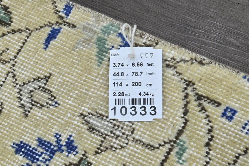 May include: A beige rug with a floral pattern in shades of blue, green, and brown. The rug is 3.74 feet by 6.56 feet, 44.8 inches by 78.7 inches, or 114 cm by 200 cm. The rug weighs 4.34 kg.