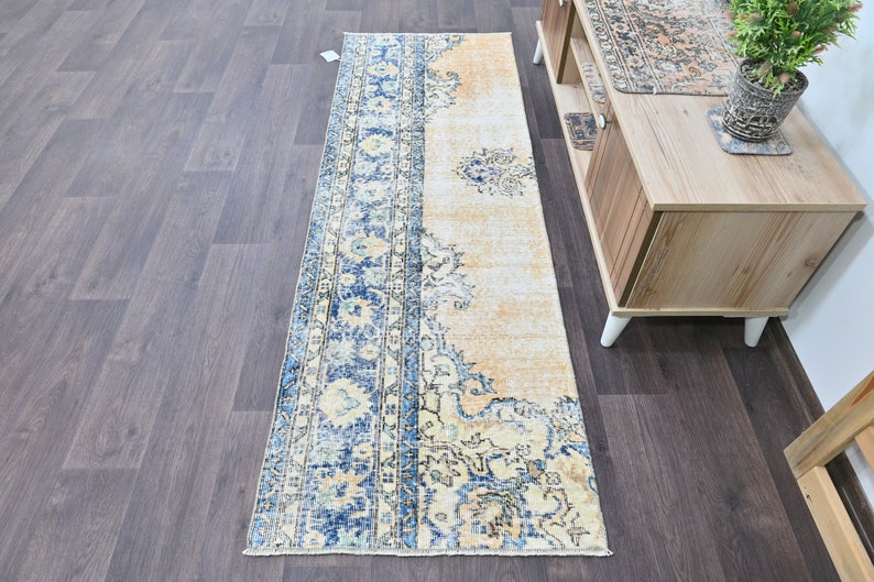 Op de afbeelding: Een vintage stijl loper met een blauw en cr&egrave;me bloemenpatroon. De loper heeft een verweerde look en is perfect om een ​​bohemien stijl aan je huis toe te voegen.
